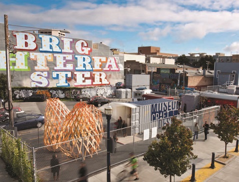 A two-block area inhabited by food and retail vendors housed in temporary buildings constructed from recycled, gaily painted shipping containers.