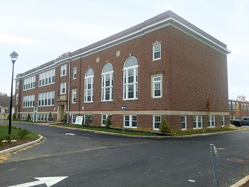 A former red brick schoolhouse with white trim converted to 32 senior apartments.