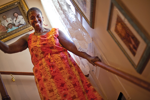 An older woman descends the stairs in her home, using the handrail installed for her safety.