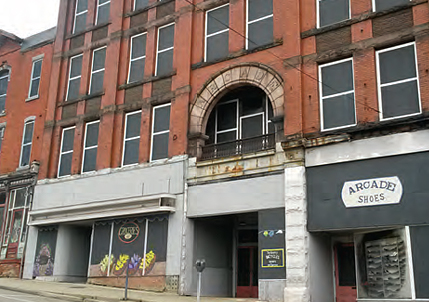 A building with vacant commercial spaces at ground level in which an artist has painted windows and storefronts to create an attractive façade.  