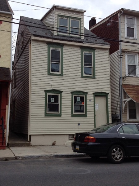 Photograph displaying the front façade of a multistory home with a gable fronted dormer protruding from the attic.