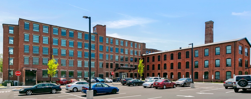 Photo of a brick building with a parking lot in front.