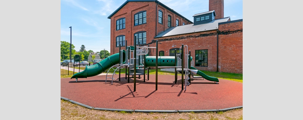 Picture of a playground in front of a brick building.