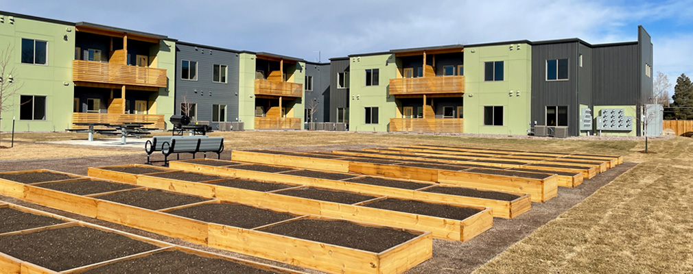 A low-rise apartment building as seen from the interior courtyard, which includes large, empty planters for a community garden.