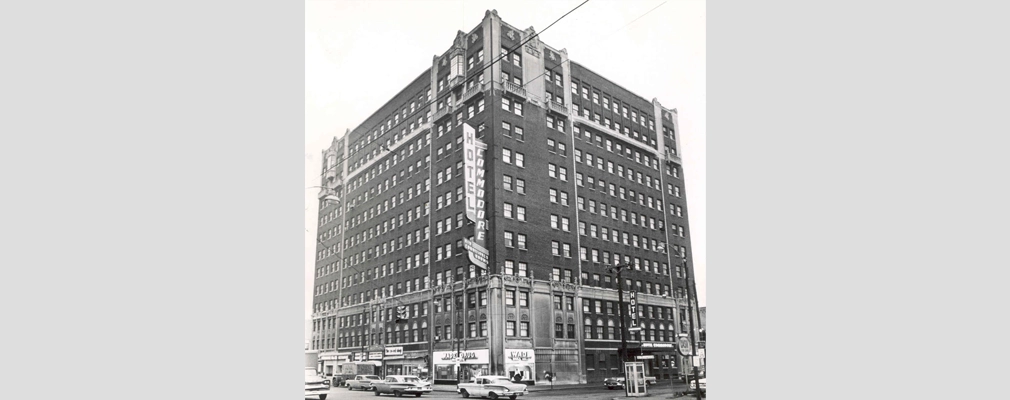 A black-and-white photograph of a 13-story brick building with the sign 'Hotel Commodore'.