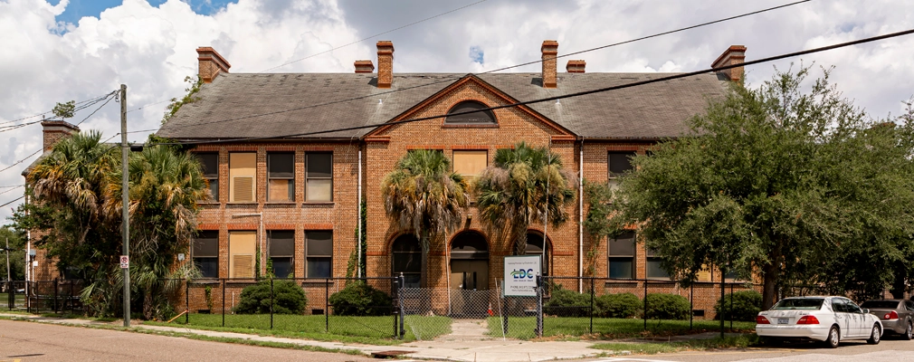 Two-story, red-brick building with boarded-up windows.