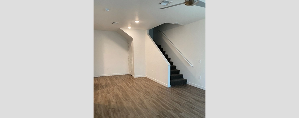 Unfurnished room with vinyl plank floors, a staircase, and a door.  