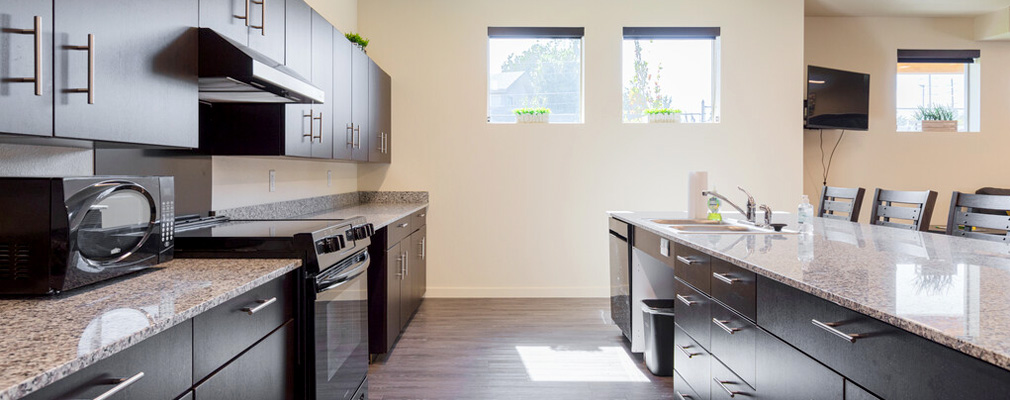 A modern communal kitchen area with granite countertops.