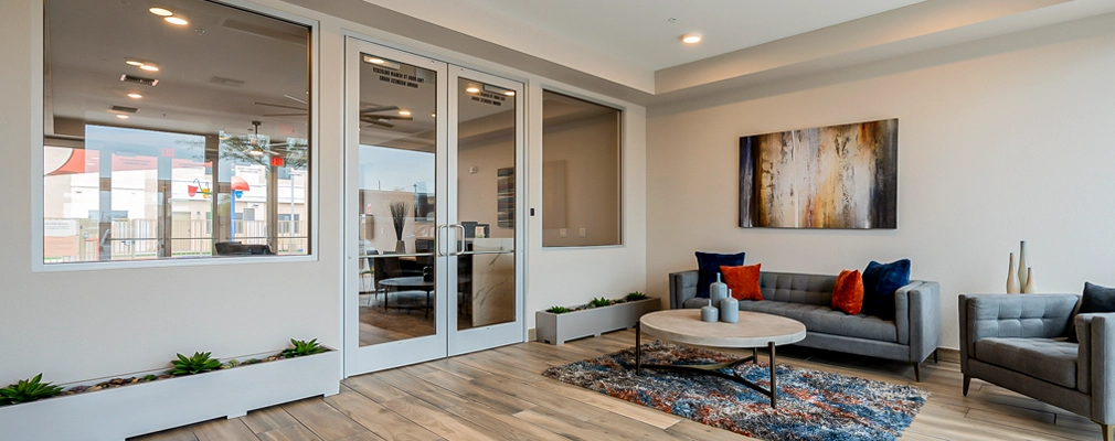 Community room with a large window, sofa, chair, table, and large painting.