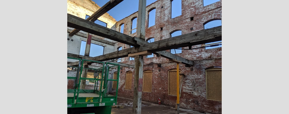  Photo of a wooden substructure in a gutted brick building.