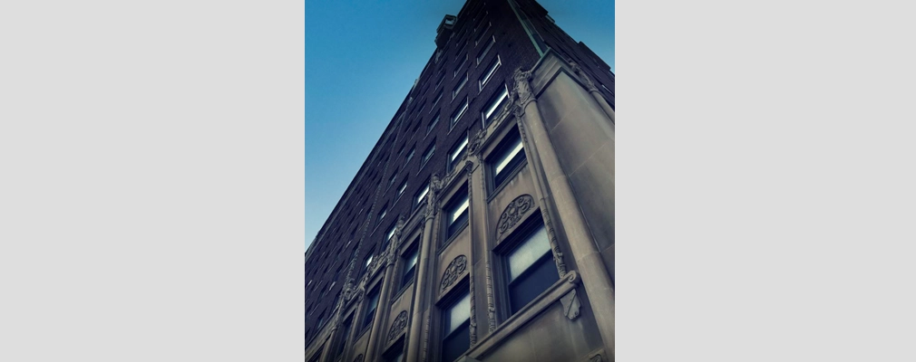 A close-up photograph shows the Tudor Revival–style stone details on the exterior of a building.