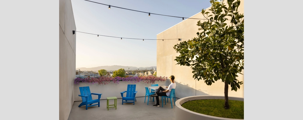 A resident enjoying a view of nearby mountains from a landscaped outdoor seating area.