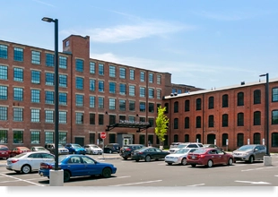 Photo of a brick building with a parking lot in front.