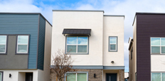 Front view of a row of townhomes and a street in the foreground.