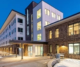 Four-story apartment building with a covered entrance and snow in the foreground.