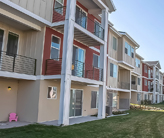 Grassy terrain and a pathway with residential buildings to the left and right.