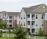 An apartment complex with trees and a lawn in the foreground.