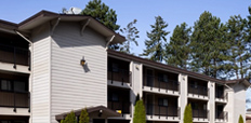 An angled view of Henry House, the multifamily rental apartment, with a parking lot in front.