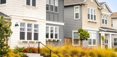 A row of single family homes with stairs and a sidewalk in front.