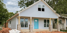 Single-family home with unfinished front yard covered with red rocks.