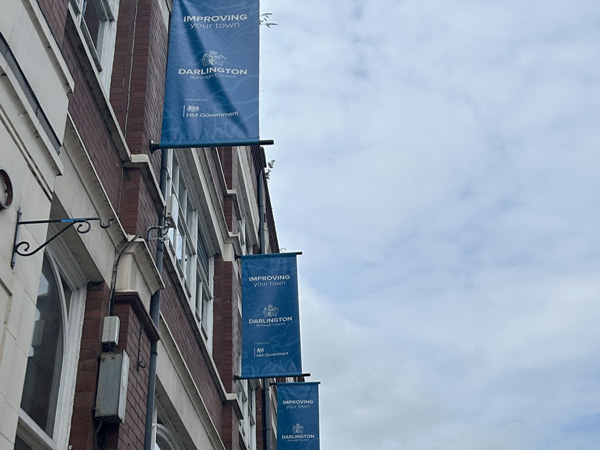 Civic banners adorning exterior of a brick building.