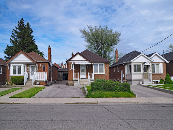 Front view of a row of single-story houses and a street in the foreground.