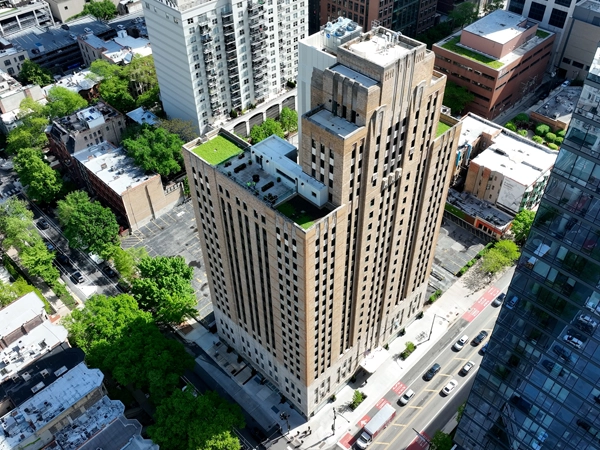 Aerial view of 24-story beige building surrounded by other buildings.