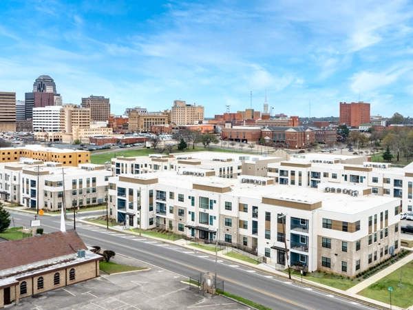 Oblique aerial view of several three-story apartment buildings with downtown Shreveport in the background.