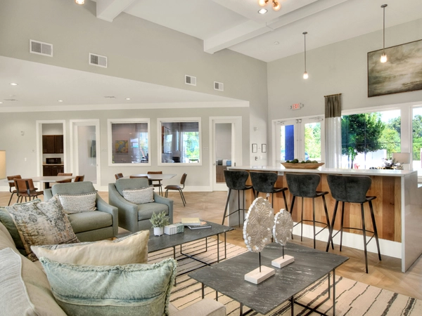 Interior community room with a sofa, chairs, and a counter with barstools.