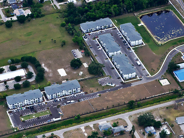 Aerial view of an apartment complex with six low-rise buildings.