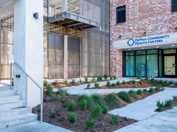 Brick building with a sign reading "DePaul Community Health Centers," with stairs and a landscaped ramp in the foreground.