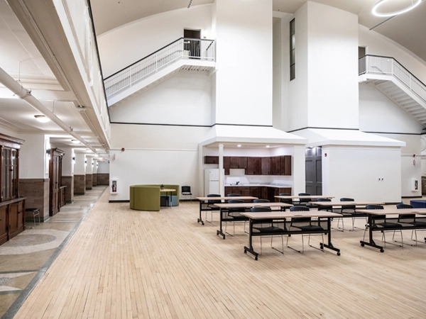 Large room with tables and chairs and a kitchen in the background.