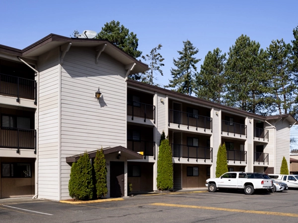 An angled view of Henry House, the multifamily rental apartment, with a parking lot in front.