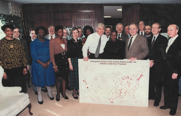 PD&R staff standing together, with two people holding a large map that reads "Enterprise Zones in the United States Under the Kasten/Lieberman Proposal."