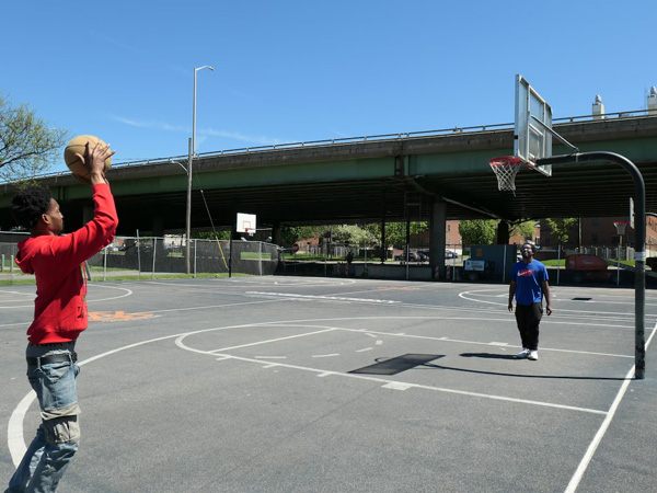 At a basketball court on Wilson Park, Quenton House shoots a basket as Savon Clanton waits for the rebound.