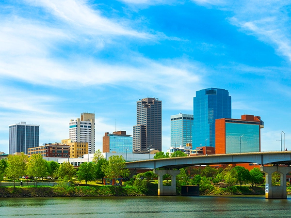 Photo of downtown Little Rock, Arkansas, as seen from across a river with a bridge in the foreground.