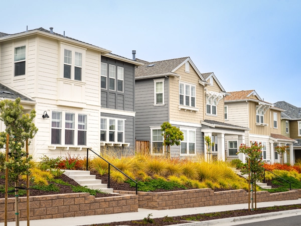 A row of single family homes with stairs and a sidewalk in front.