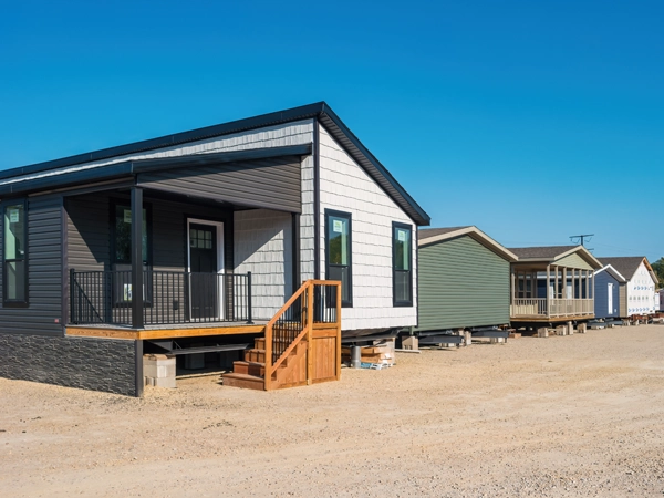 A row of prefabricated modular houses in a dirt lot.