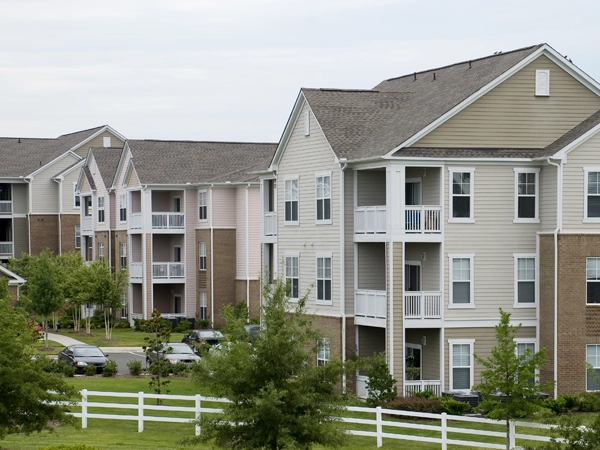 An apartment complex with trees and a lawn in the foreground.